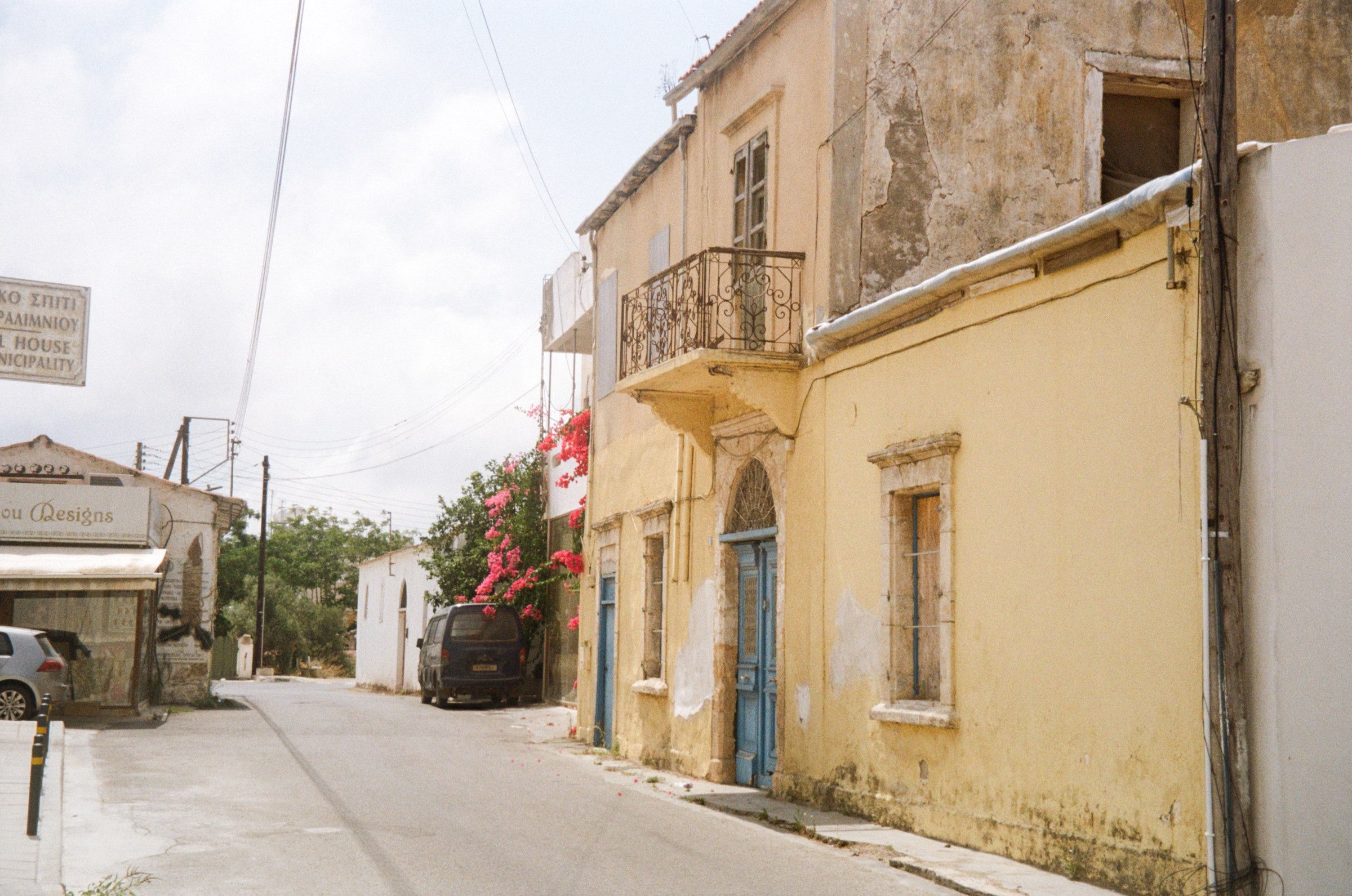 A weathered street in the old town with a blue door and bougainvillea